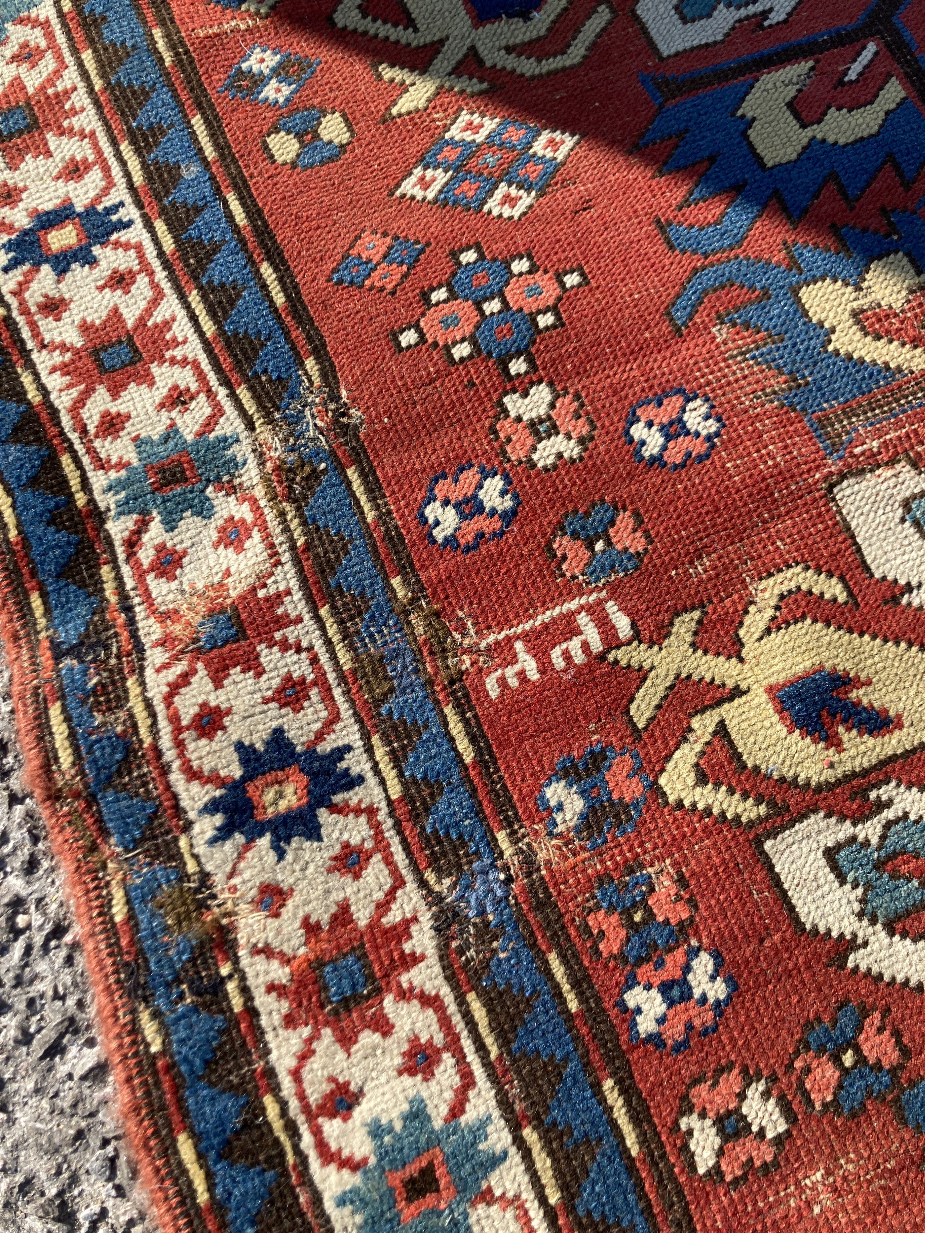 An early 20th century Caucasian “Eagle” Kazak brick red ground rug with triple medallion (altered) 230 x 134 cms.